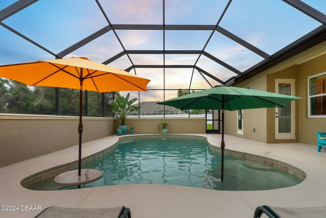 pool at dusk with a patio and a lanai