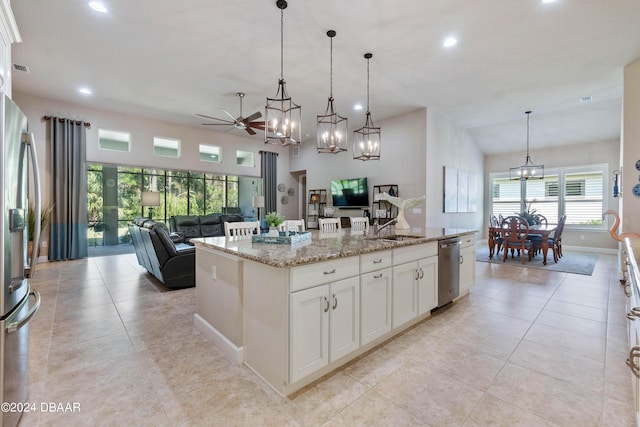 kitchen with appliances with stainless steel finishes, decorative light fixtures, an island with sink, white cabinets, and light stone counters