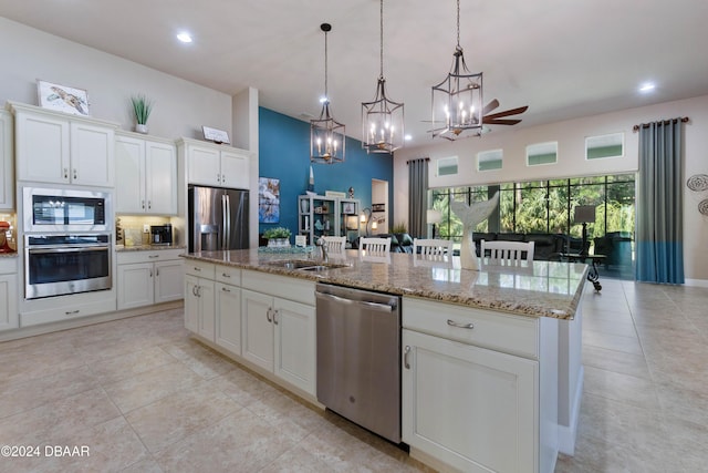 kitchen featuring stainless steel appliances, sink, a kitchen island with sink, and hanging light fixtures