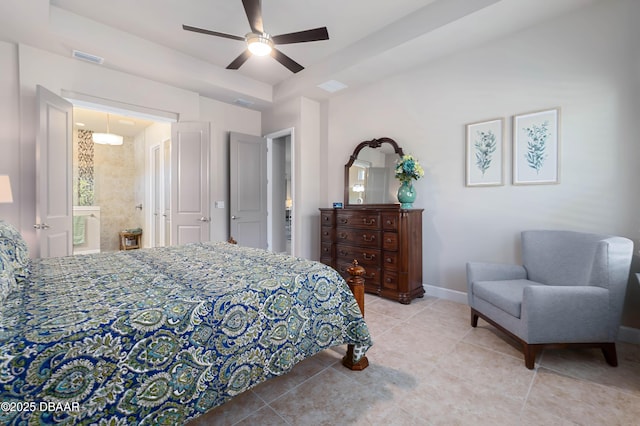 bedroom with ceiling fan, connected bathroom, a tray ceiling, and light tile patterned floors