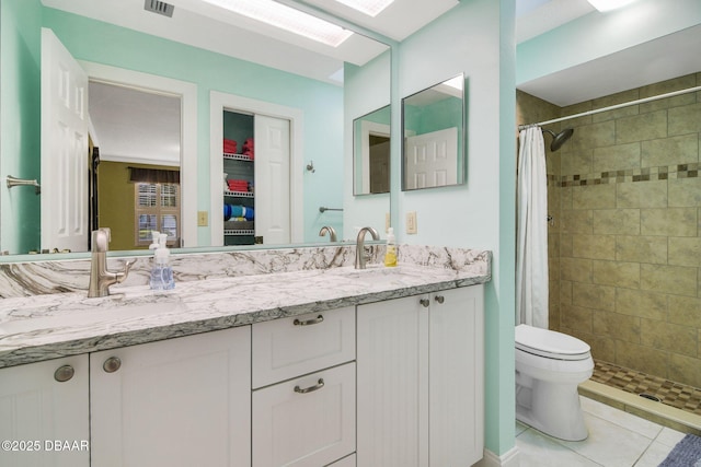 bathroom featuring toilet, a skylight, vanity, curtained shower, and tile patterned flooring