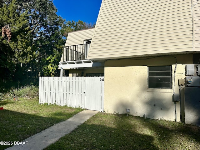 view of home's exterior featuring a balcony and a lawn