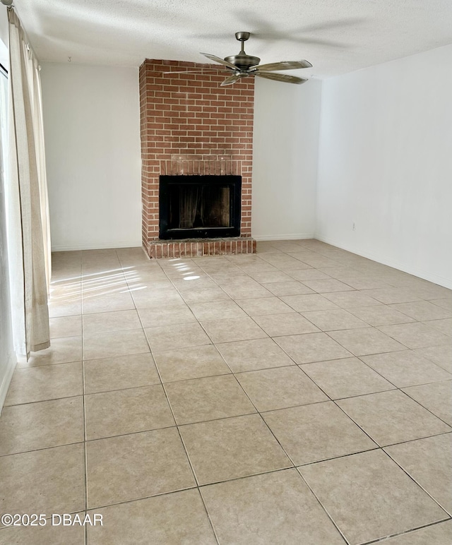 unfurnished living room featuring light tile patterned flooring, a brick fireplace, a textured ceiling, and ceiling fan