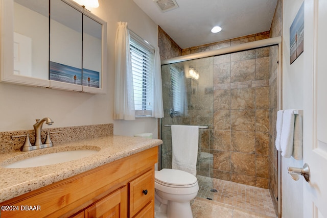 bathroom featuring toilet, vanity, tile patterned floors, and a shower with shower door