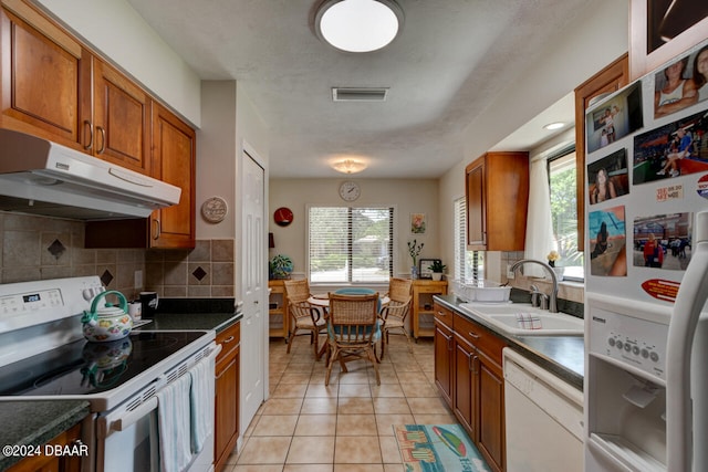 kitchen featuring plenty of natural light, light tile patterned floors, white appliances, and sink