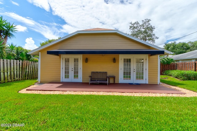 back of property with a lawn, french doors, and a deck