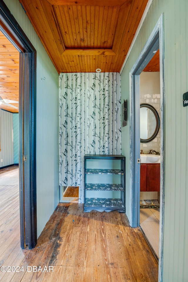 hall featuring wooden ceiling, hardwood / wood-style flooring, wooden walls, and sink