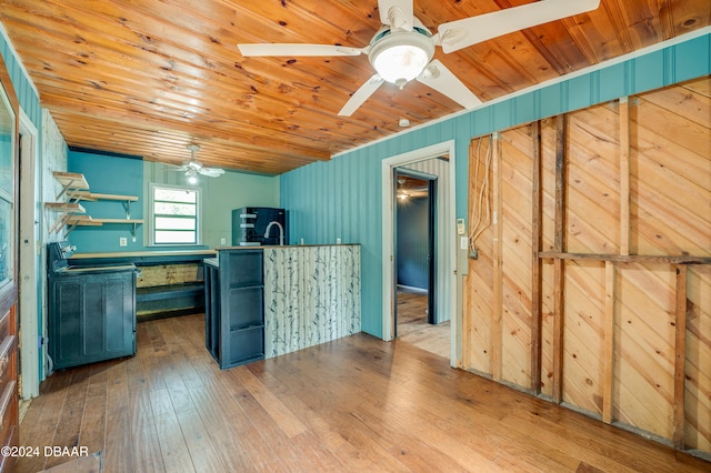 kitchen featuring wooden ceiling, blue cabinets, black refrigerator, wooden walls, and light wood-type flooring