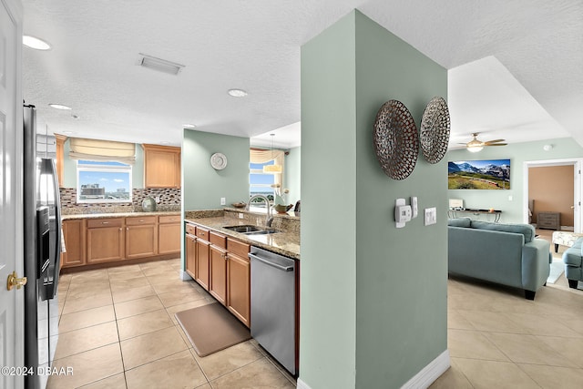 kitchen featuring stainless steel dishwasher, light stone countertops, a textured ceiling, and sink