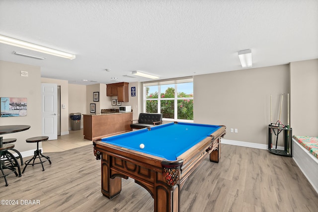 rec room with billiards, light hardwood / wood-style flooring, and a textured ceiling