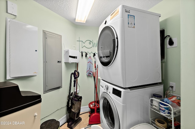 clothes washing area featuring stacked washing maching and dryer, electric panel, and a textured ceiling