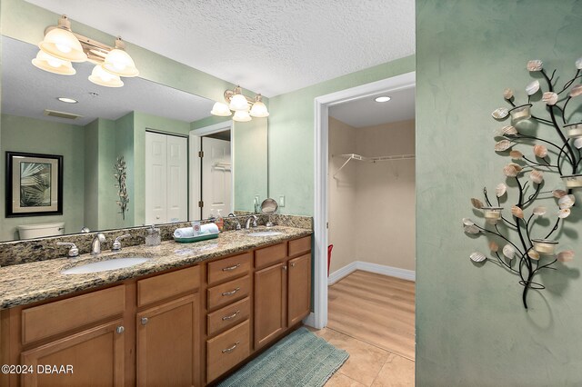 bathroom featuring wood-type flooring, a textured ceiling, toilet, and vanity