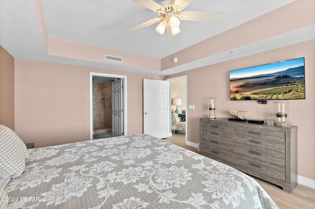 bedroom with light hardwood / wood-style flooring, ceiling fan, and ensuite bath