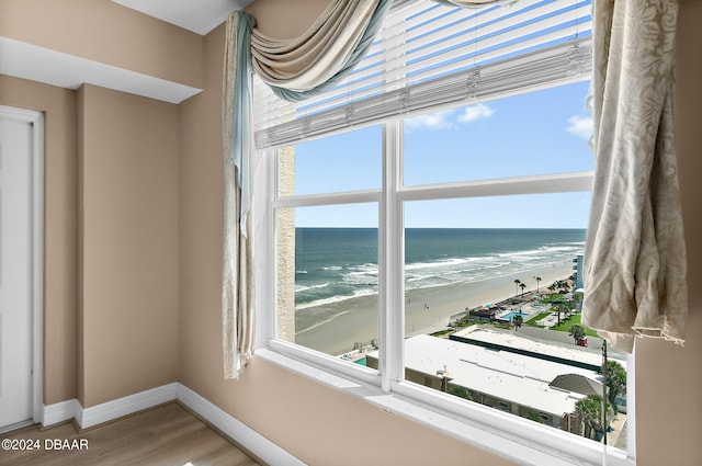 room details featuring hardwood / wood-style flooring, a water view, and a view of the beach