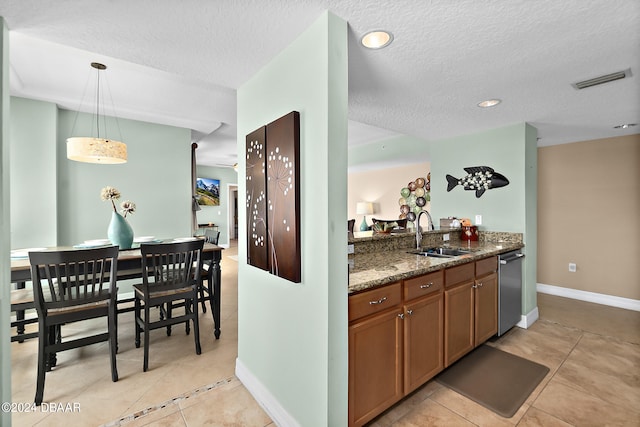 kitchen with a textured ceiling, hanging light fixtures, sink, dishwasher, and dark stone countertops