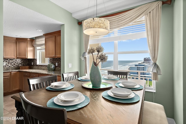 dining space featuring light tile patterned flooring and a water view