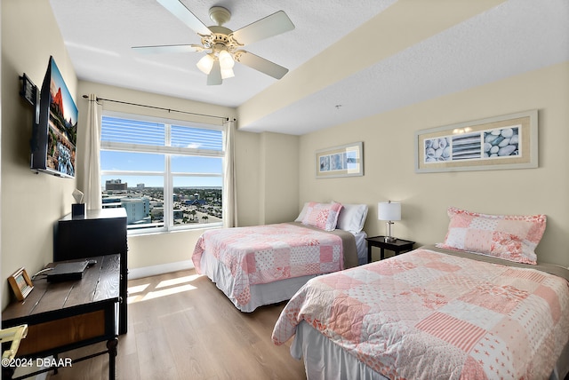 bedroom with ceiling fan, wood-type flooring, and a textured ceiling