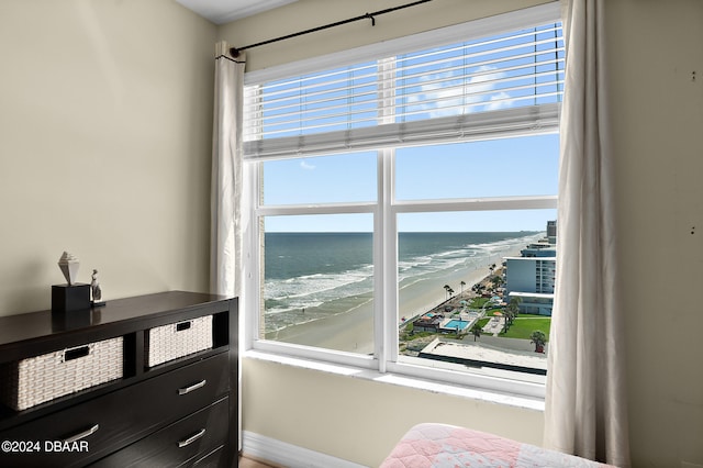 bedroom featuring multiple windows, a beach view, and a water view