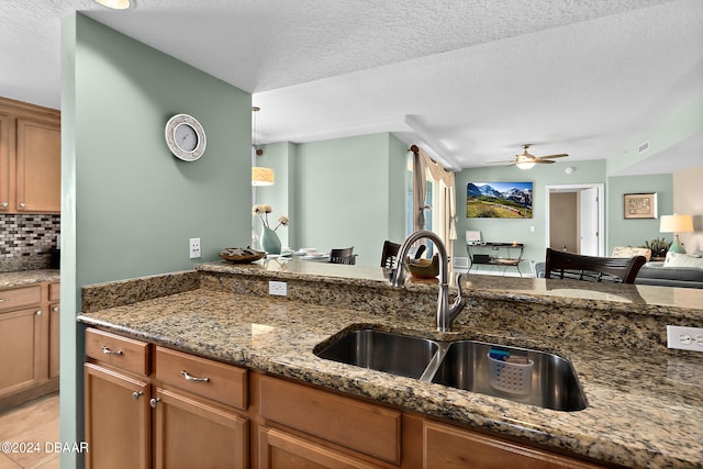 kitchen featuring dark stone counters, tasteful backsplash, and a textured ceiling