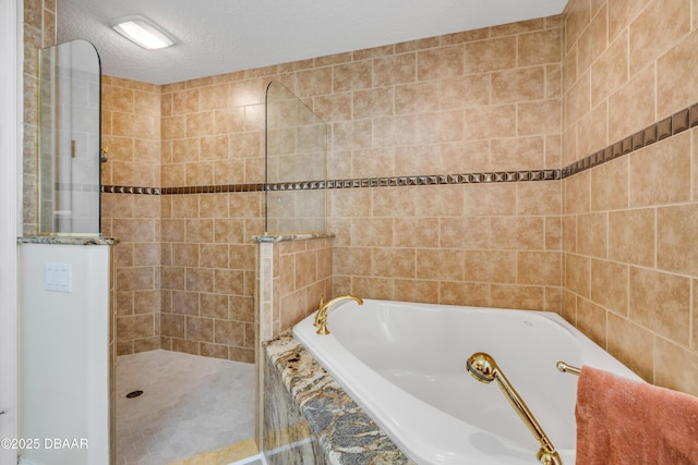100 Emerald Lake Dr, Palm Coast, FL 32137 - bathroom featuring a bath, walk in shower, a textured ceiling, and tile walls