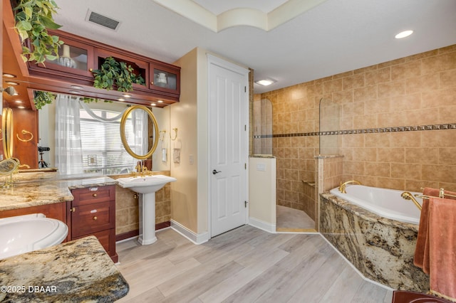 100 Emerald Lake Dr, Palm Coast, FL 32137 - full bath featuring wood finished floors, a garden tub, walk in shower, baseboards, and recessed lighting