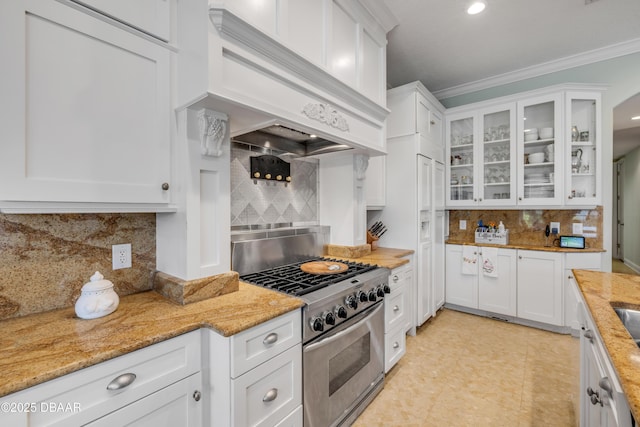 100 Emerald Lake Dr, Palm Coast, FL 32137 - kitchen with stainless steel gas range oven, backsplash, custom range hood, white cabinets, and crown molding
