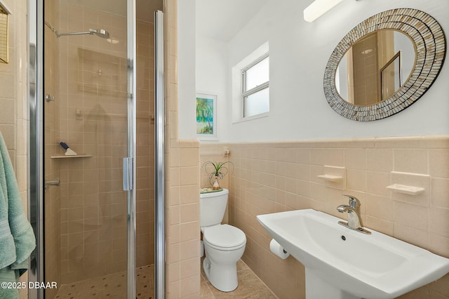 bathroom featuring tile walls, sink, a shower with door, and toilet