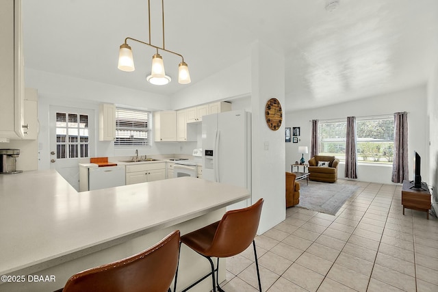 kitchen with sink, light tile patterned floors, white cabinets, vaulted ceiling, and kitchen peninsula