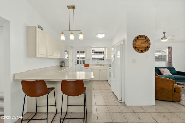 kitchen with white cabinetry, sink, white appliances, and kitchen peninsula