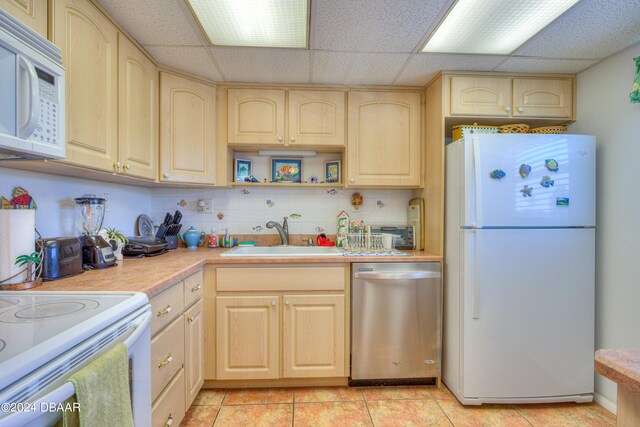 kitchen featuring light tile patterned flooring, a paneled ceiling, light brown cabinets, sink, and white appliances