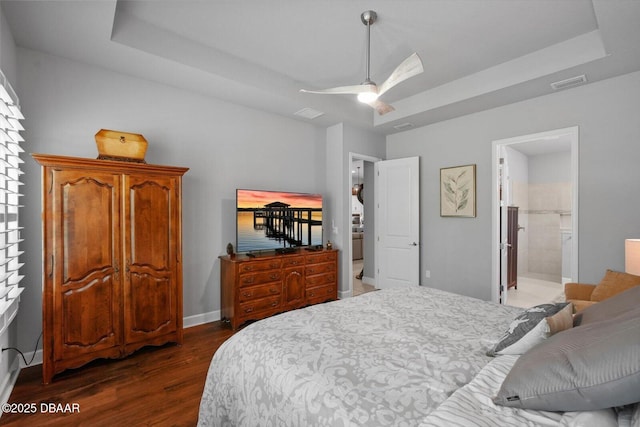 bedroom featuring baseboards, a tray ceiling, dark wood-style floors, and visible vents