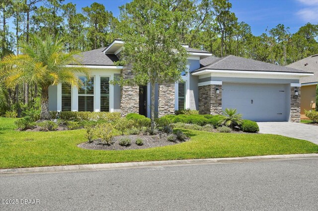 view of front facade with stone siding, a front yard, stucco siding, an attached garage, and driveway