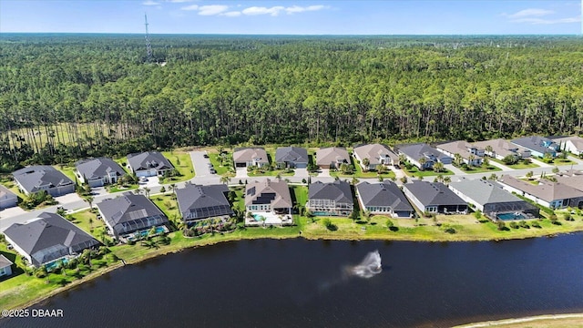 drone / aerial view with a water view, a view of trees, and a residential view