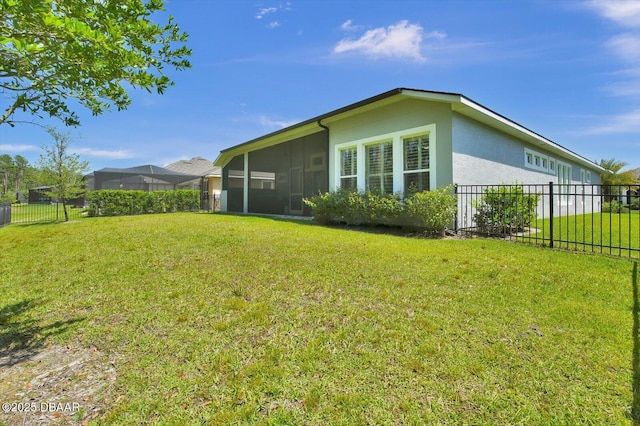 view of home's exterior featuring fence, a sunroom, stucco siding, and a yard
