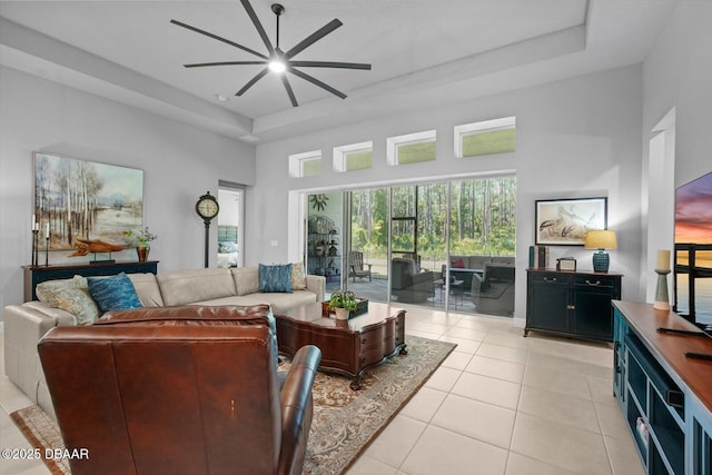 living room featuring a raised ceiling, a ceiling fan, light tile patterned flooring, and a towering ceiling