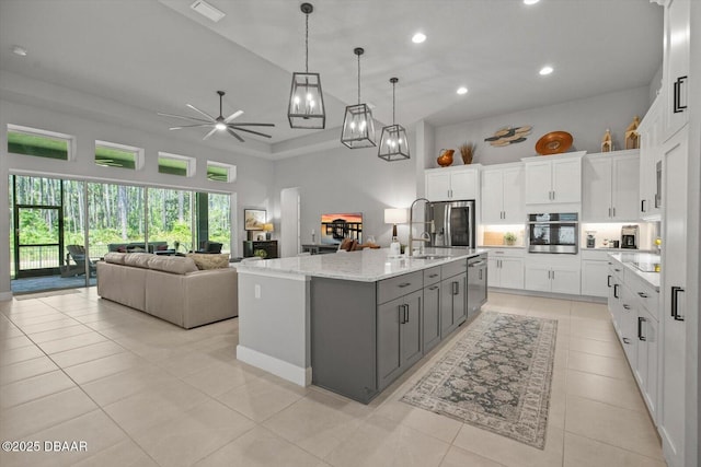 kitchen with ceiling fan with notable chandelier, stainless steel appliances, recessed lighting, light tile patterned floors, and a towering ceiling