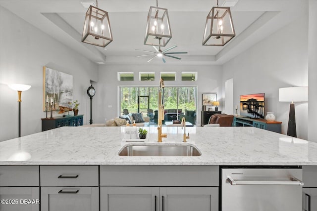 kitchen featuring a sink, light stone counters, dishwasher, and open floor plan