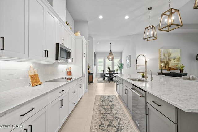 kitchen with a sink, stainless steel appliances, recessed lighting, white cabinetry, and backsplash