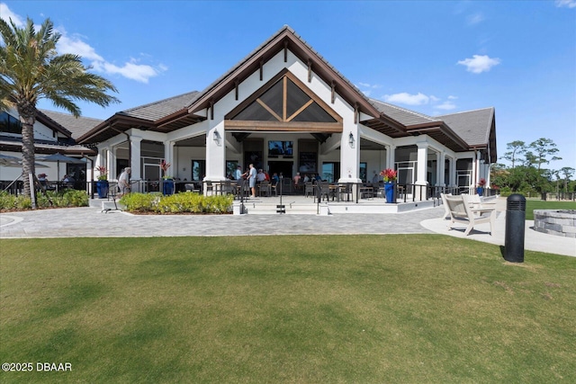 back of property featuring a lawn, a patio area, and a tile roof