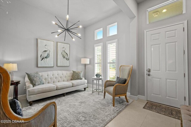 tiled living area featuring baseboards, a high ceiling, and a chandelier