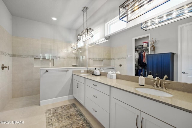 bathroom with double vanity, a sink, walk in shower, and a spacious closet