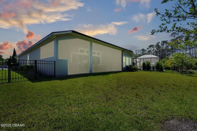 property exterior at dusk featuring fence and a yard