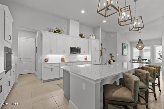 kitchen with a sink, stainless steel appliances, white cabinetry, and a chandelier