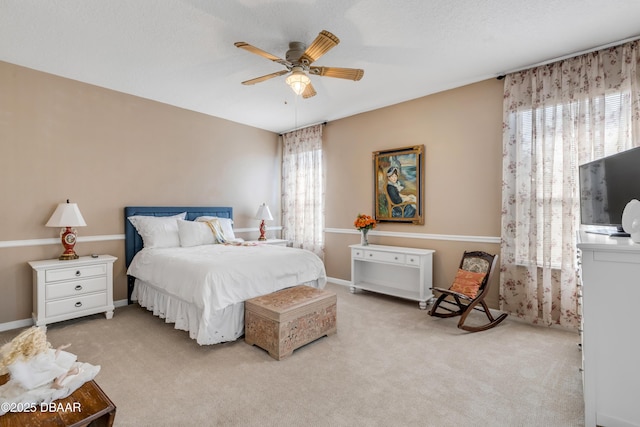 bedroom with ceiling fan, light carpet, and a textured ceiling