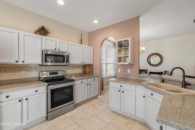 kitchen featuring white cabinetry, sink, light tile patterned floors, and appliances with stainless steel finishes