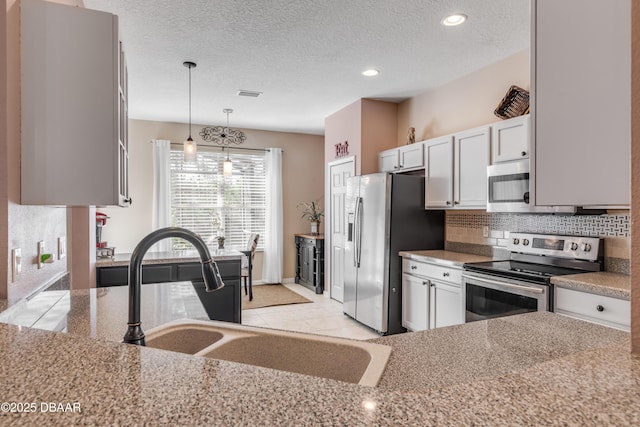 kitchen featuring appliances with stainless steel finishes, decorative light fixtures, tasteful backsplash, white cabinetry, and sink