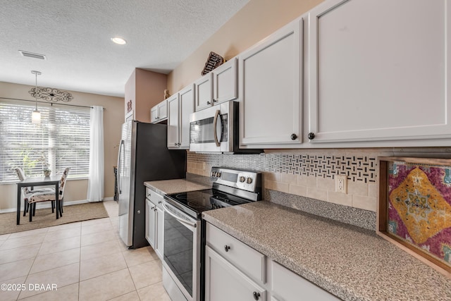 kitchen featuring white cabinetry, appliances with stainless steel finishes, hanging light fixtures, and light tile patterned floors