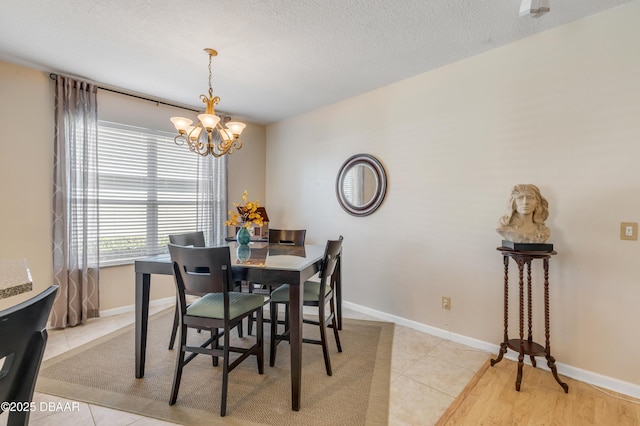 dining area featuring light tile patterned flooring, an inviting chandelier, and a textured ceiling