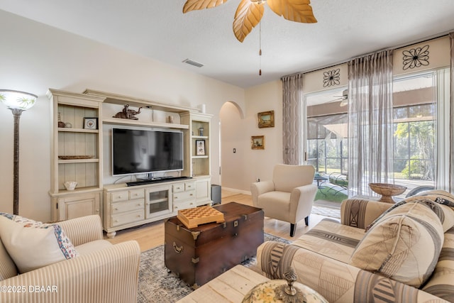 living room with ceiling fan, a textured ceiling, and light hardwood / wood-style floors