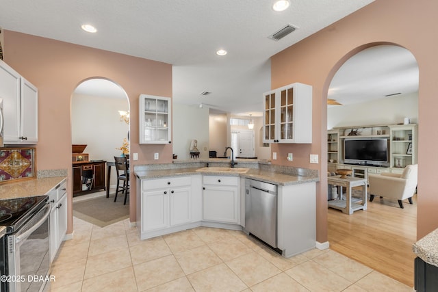 kitchen featuring sink, light tile patterned floors, white cabinetry, stainless steel appliances, and light stone counters